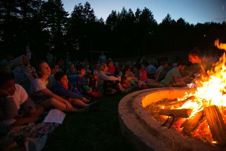 Kids and counselors sitting around a campfire