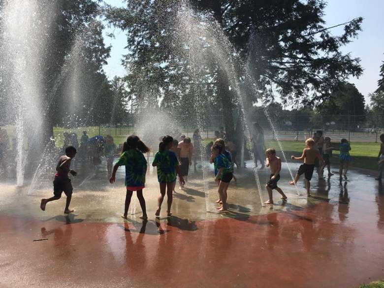 several kids playing in sprinklers