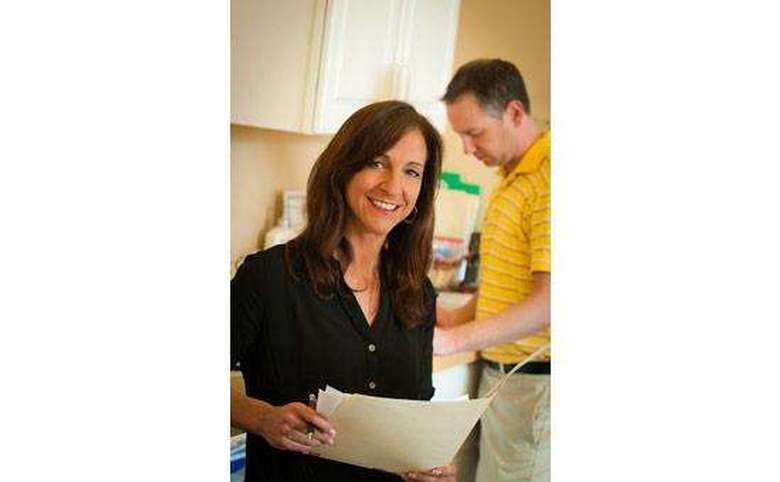 Woman in a room smiling holding  files