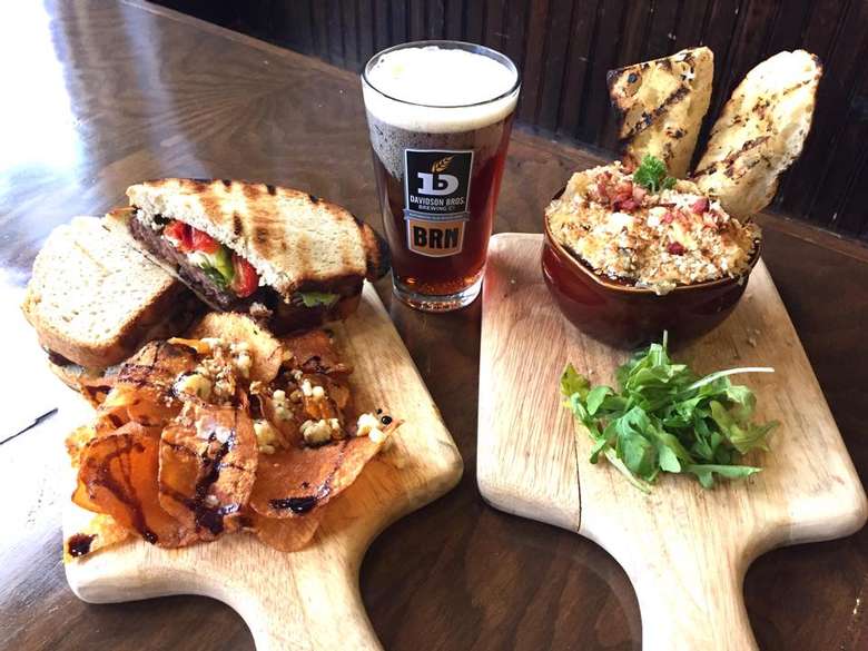 glass of beer and sandwiches and food on two wooden platters