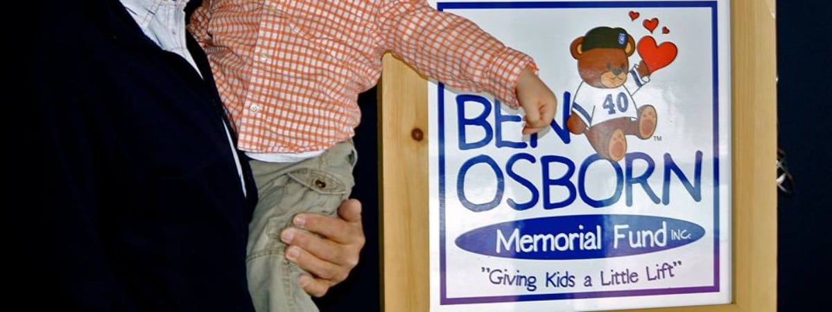 man holding up little boy in front of Ben Osborn sign