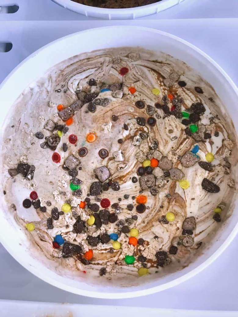 a lot of toppings and candy on a bucket of ice cream