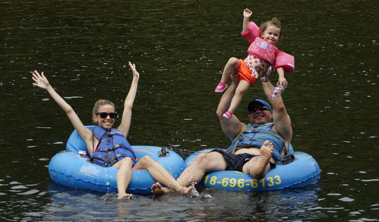 two people in blue tubes, a man is holding up a girl
