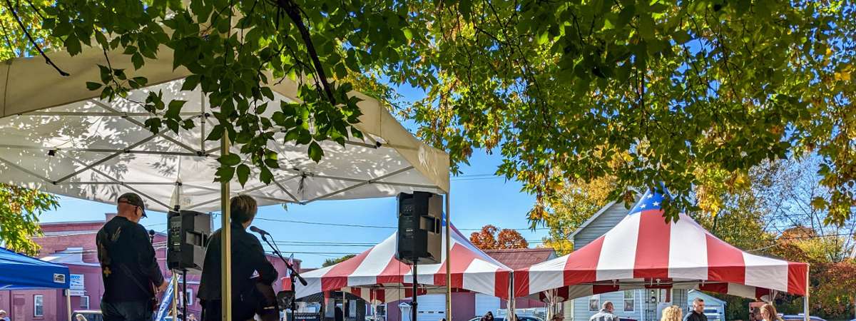 band plays at festival, people eat at picnic tables