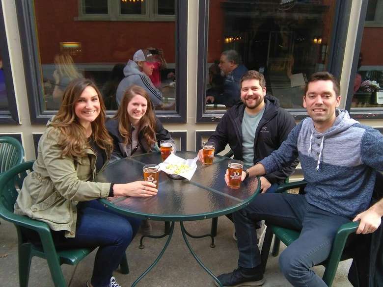 four people at a patio table with beer