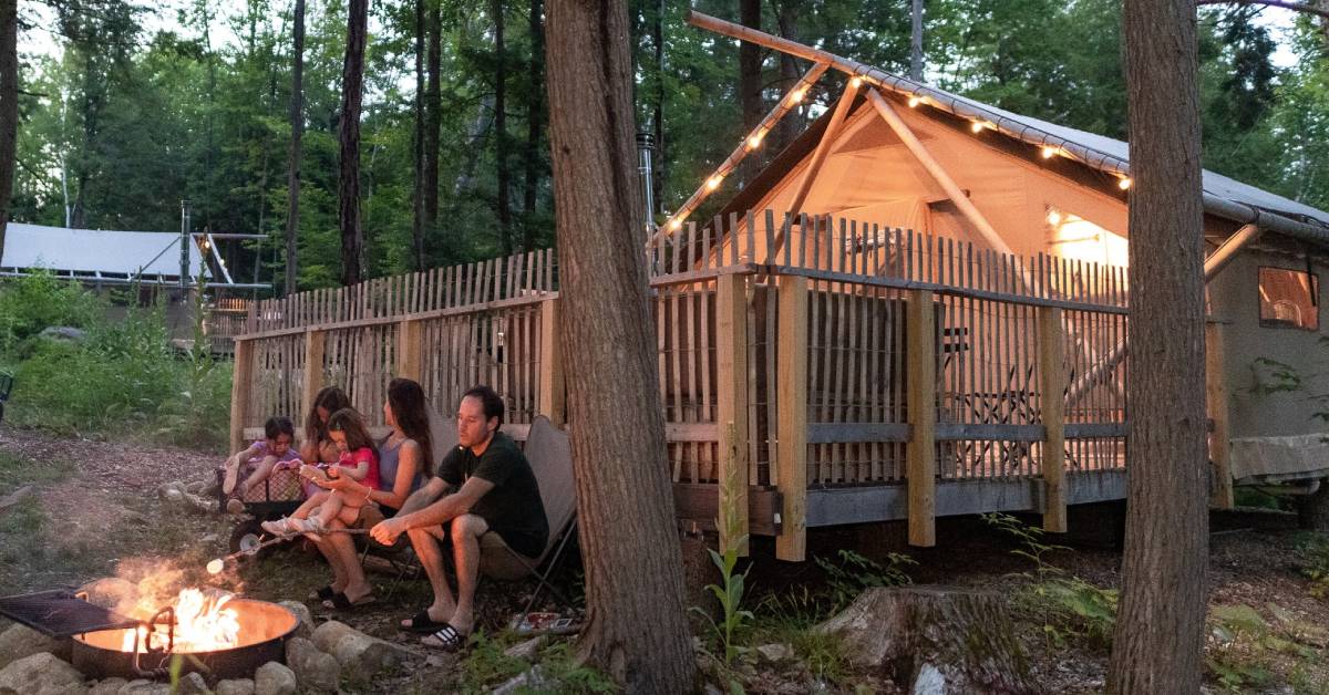 people at a campfire at huttopia adirondacks