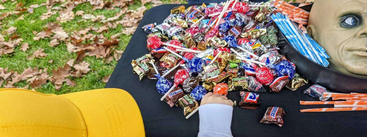 closeup of kid grabbing a lollipop off a table with a fake severed head