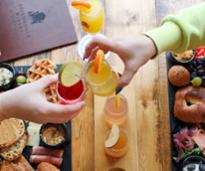 hands cheersing cocktails over brunch boards