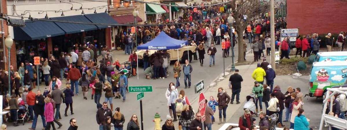 crowd of people walking around a city during an event