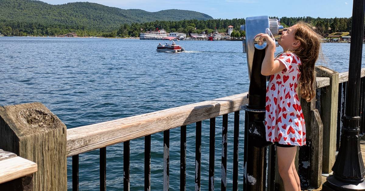 little girl looks through view finder in lake george
