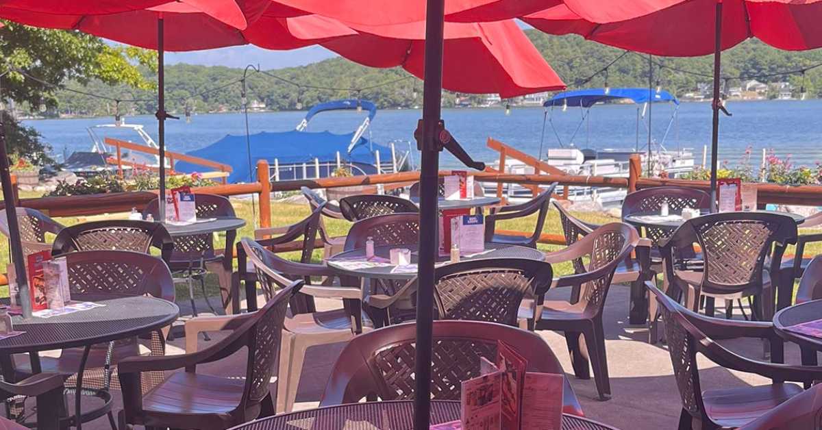 tables and chairs with red umbrellas by a lake