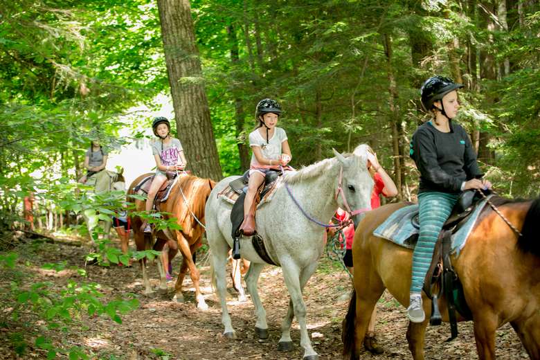 Girls horseback riding through the woods