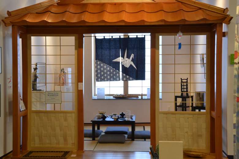 Japanese exhibit in a museum complete with low table, pillows for sitting, and more traditional decor
