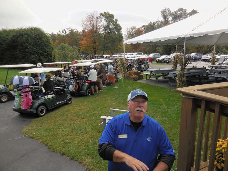 several golf carts loaded with people and gear before a tournament