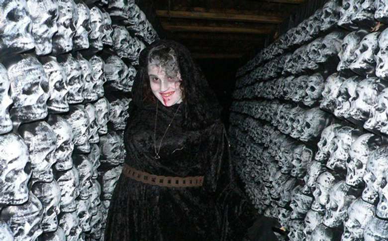 scary woman standing in hallway of skulls