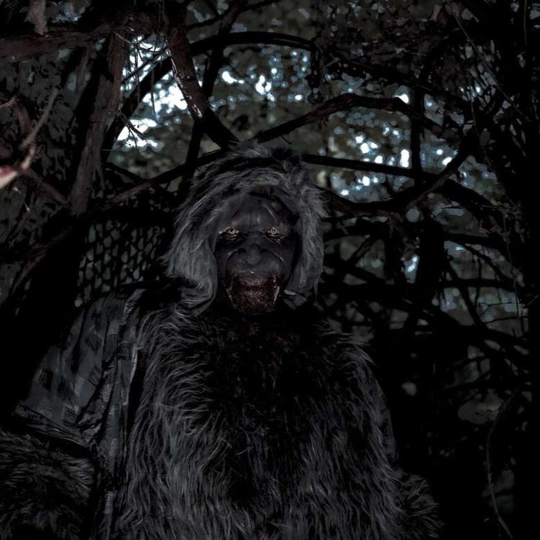 man dressed in scary costume in a forested area