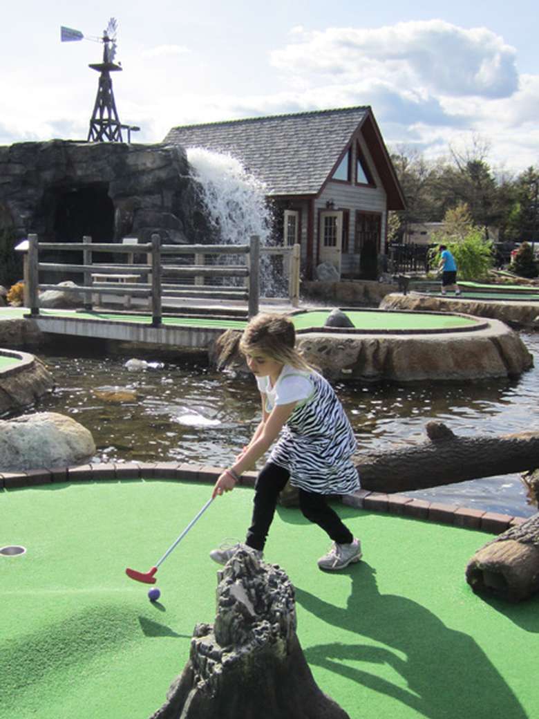 a little girl playing mini golf