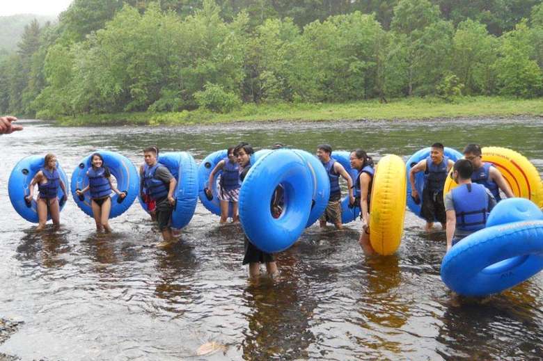 group of people standing up in a river holding up tubes
