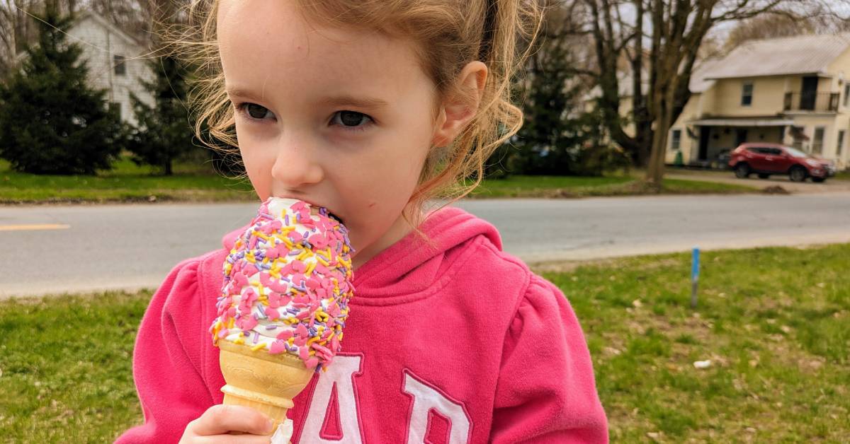 little girl eating ice cream cone with unicorn sprinkles