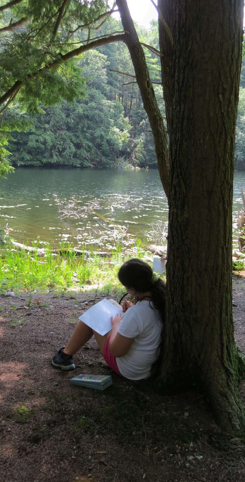 girl sketches leaning against a tree