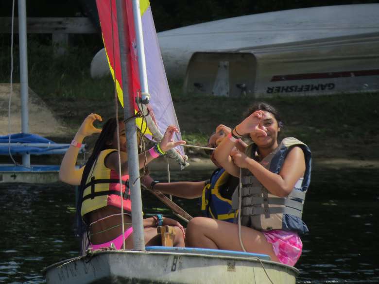 campers hold up hearts while sailing