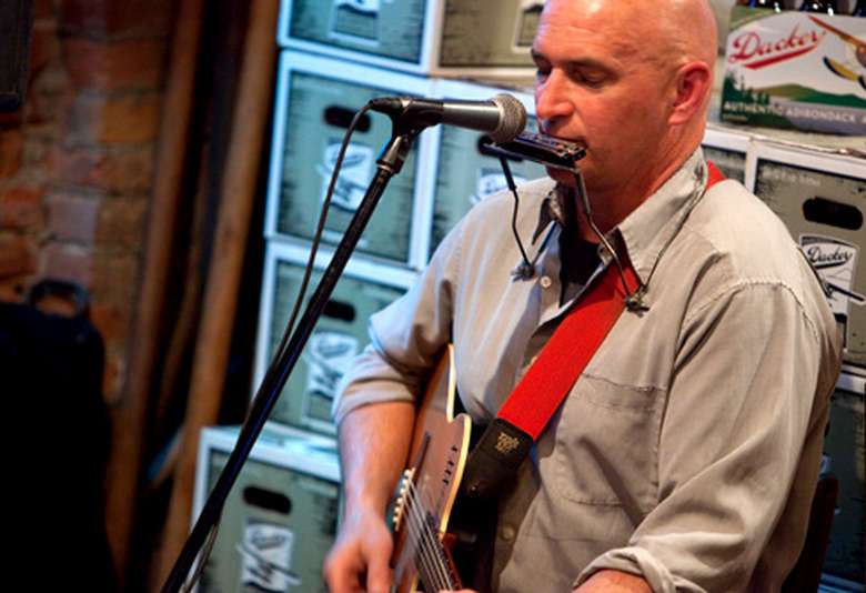 man with harmonica and acoustic guitar