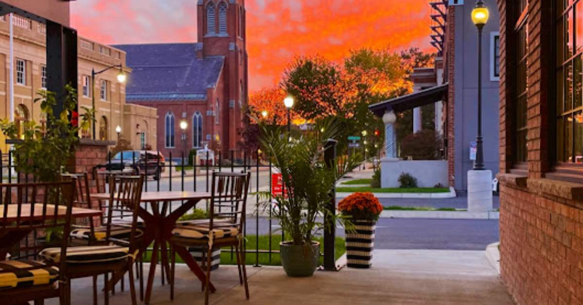 sunset over city and tables with chairs outside a restaurant