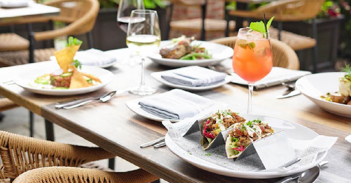 table with cocktails, wine and plates on it outdoors