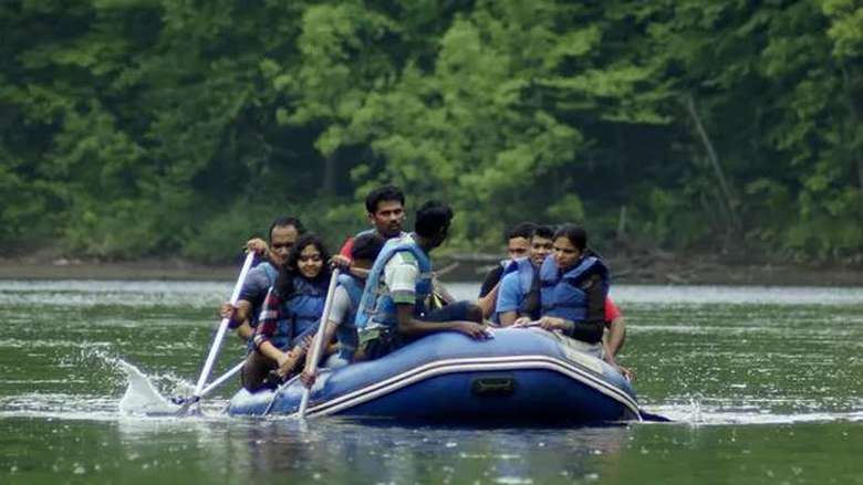 a fairly large group of people in a single raft on a river