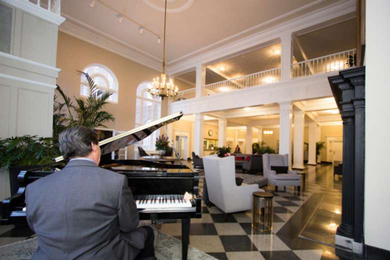 man playing piano in the lobby at the queensbury hotel