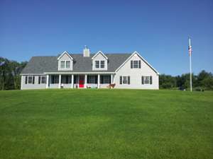 new house with gray siding, a red front door, and a large lawn in front